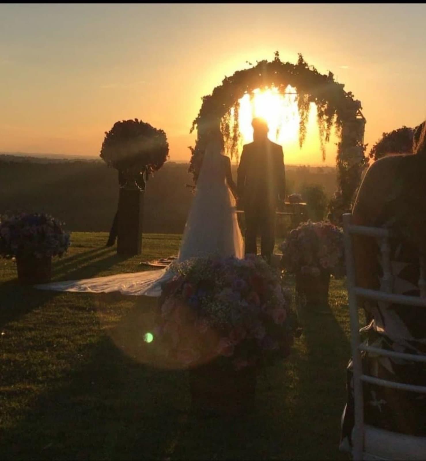 Cerimônia de casamento ao pôr do sol sob arco de flores na Xakara Eventos