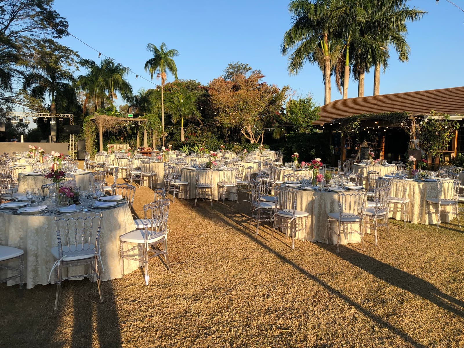 Mesas de casamento montadas no gramado, na época do salão de sapê